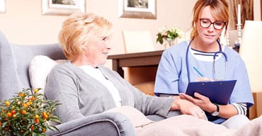 A woman sitting on the couch talking to another person.